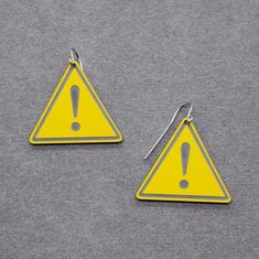 two yellow triangle shaped earrings with an exclamation sign on them