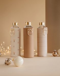 three bottles are lined up on a table with ornaments around them and one is empty