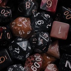 many different colored and black dices are stacked on top of each other, with numbers painted on them