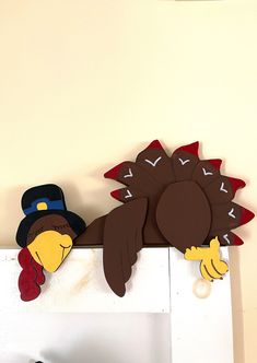 two turkeys are sitting on top of a fireplace mantel, one is wearing a hat and the other has a fake turkey