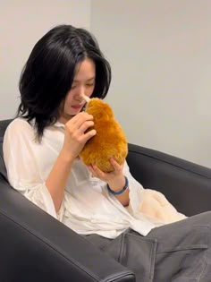 a woman sitting in a chair holding a teddy bear