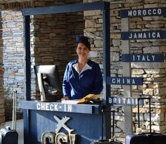 a woman standing behind a check in counter with luggage on the ground next to her