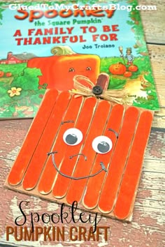 popsicle pumpkin craft with a book in the background and an image of a face on it