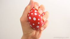 a hand holding a red and white polka dot easter egg