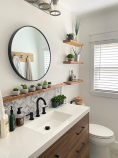 a bathroom with a sink, mirror and shelves on the wall next to the toilet