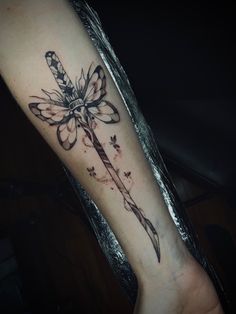 a tattoo on the arm of a person with a knife and dragonfly in it