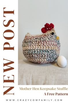 a crocheted chicken sitting next to an egg on top of a tablecloth