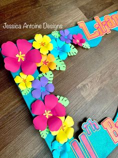 the letter f is made out of paper and decorated with colorful flowers on a wooden floor