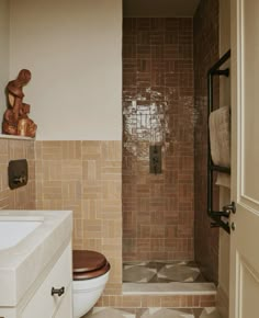 a bathroom with a toilet, sink and tiled walls