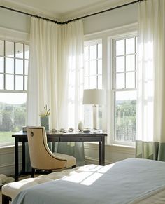 a bedroom with two windows and a chair in front of the window, along with a desk