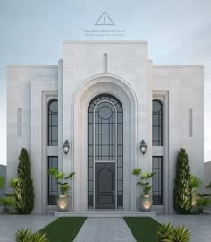 a large white building with an arched door and two planters on the front lawn