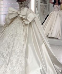 a woman in a wedding dress looking at herself in the mirror with her back to the camera