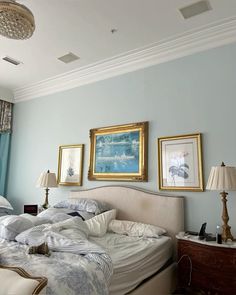 two beds in a bedroom with blue walls and pictures on the wall next to them