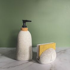 a soap dispenser and sponge sitting on a marble counter with green walls in the background