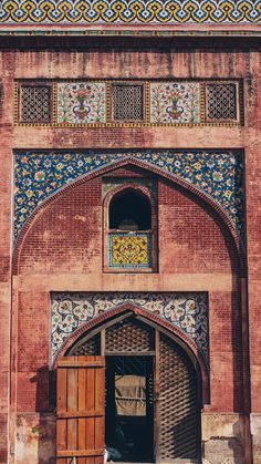 the entrance to an old building with colorful tiles on it's walls and doors