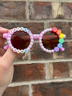 Custom name sunnies surrounded in pearls, with the cutest rainbow smiley face beads. So simple and perfect for everyday wear, or for a fun occasion. Super lightweight! Fully custom - in the personalization box, please write the child's name and which bead color you would like. If not noted, default option is black & white letters. I can also make these on flower frames - just leave me a note in the personalization box! Sunnies best fit 2-8 year olds. *Contains small parts. Though I use industria Cute Customizable Sunglasses For Gift, Custom Name Pink Sunglasses With Adjustable Fit, Pink Sunglasses With Custom Name And Adjustable Fit, Fun Pink Sunglasses For Gift, Pink Personalized Sunglasses For Gift, Pink Personalized Adjustable Sunglasses, Personalized Pink Sunglasses As A Gift, Playful Personalized Pink Sunglasses, Multicolor Plastic Sunglasses For Birthday