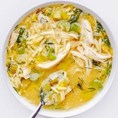 a bowl of chicken noodle soup on a white surface with a spoon in it