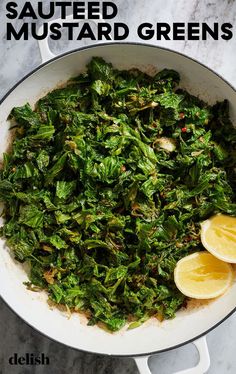 a pan filled with cooked greens and lemon wedges