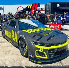 the car is painted black and yellow with numbers on it's side, as well as people standing around