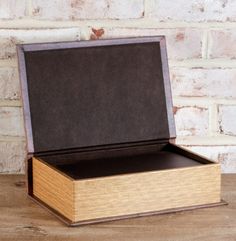 an open box sitting on top of a wooden table next to a brick wall and floor