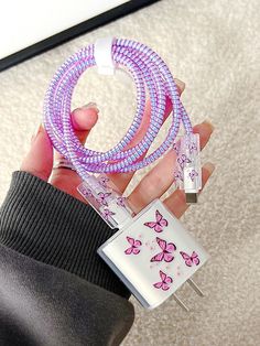 a person holding two purple and white bracelets with butterfly designs on them, in front of a mirror