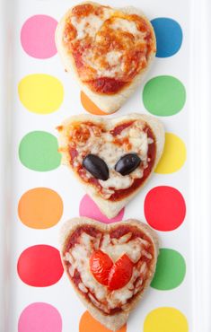 three heart shaped pizzas on a polka dot plate