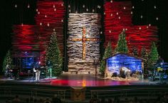 the stage is decorated with christmas decorations and lights for an event or performance, as well as a cross on it