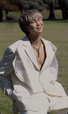 a man in a white suit standing on top of a grass covered field