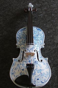 a violin with blue and white designs on it's body sitting on the ground