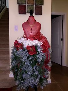 a mannequin decorated with red and white flowers on top of a table in front of stairs