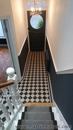 a black and white checkered floor with chandelier on the top, next to stairs