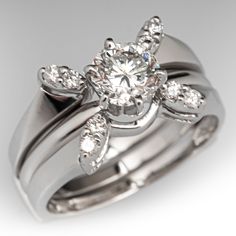 an engagement ring set with two matching bands and a flower design on the band, in white gold