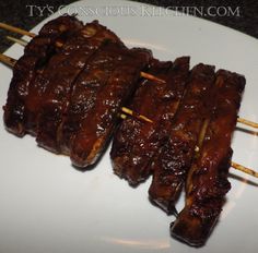 several skewered meats are sitting on a white plate