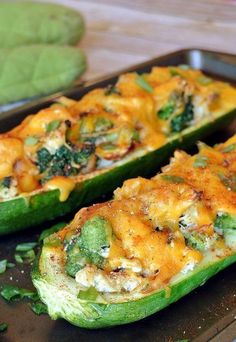 two stuffed zucchini boats with cheese and broccoli on the side, sitting on a baking sheet