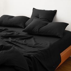 a bed with black sheets and pillows on it