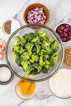 broccoli, onions and other ingredients in bowls on a marble countertop next to an assortment of condiments