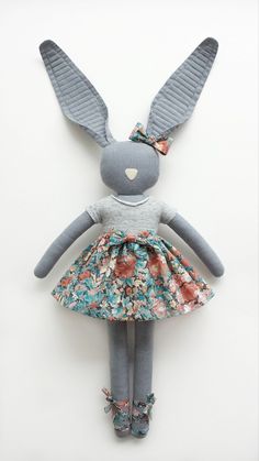 a gray stuffed animal wearing a dress and shoes with flowers on it's legs