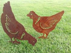 two metal roosters standing in the grass