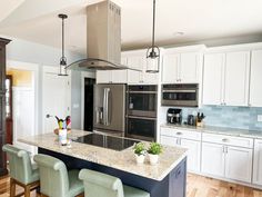 a kitchen with white cabinets, stainless steel appliances and marble counter tops is pictured in this image