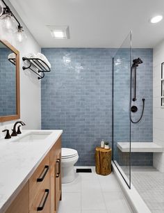 a modern bathroom with blue tile and wood accents on the walls, along with a walk in shower