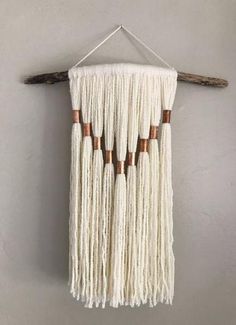 a wall hanging made out of white yarn and wooden dows on a gray wall