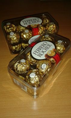 two plastic containers filled with chocolates on top of a wooden table