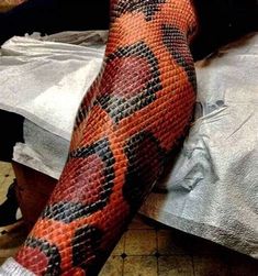 an orange and black snake skin tattoo on the arm