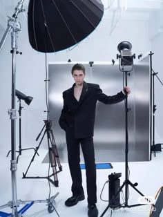 a man in a black suit is posing for a photo with his umbrella and lighting equipment