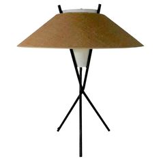 a lamp that is sitting on top of a tripod base with a light shade over it