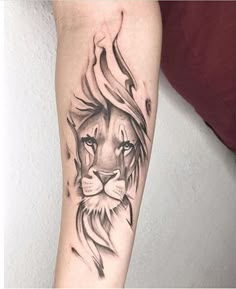 a lion tattoo on the arm with black and grey ink, it looks like he is looking