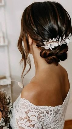 a woman wearing a bridal hair piece with flowers in her hair and holding a bouquet