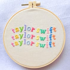 a white embroidered wall hanging with the words taylor swift, taylor swift and swift written in multicolored letters