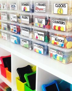 plastic bins filled with different colored items on top of a white shelf in a classroom