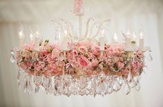 a chandelier with flowers and candles hanging from it's centerpieces